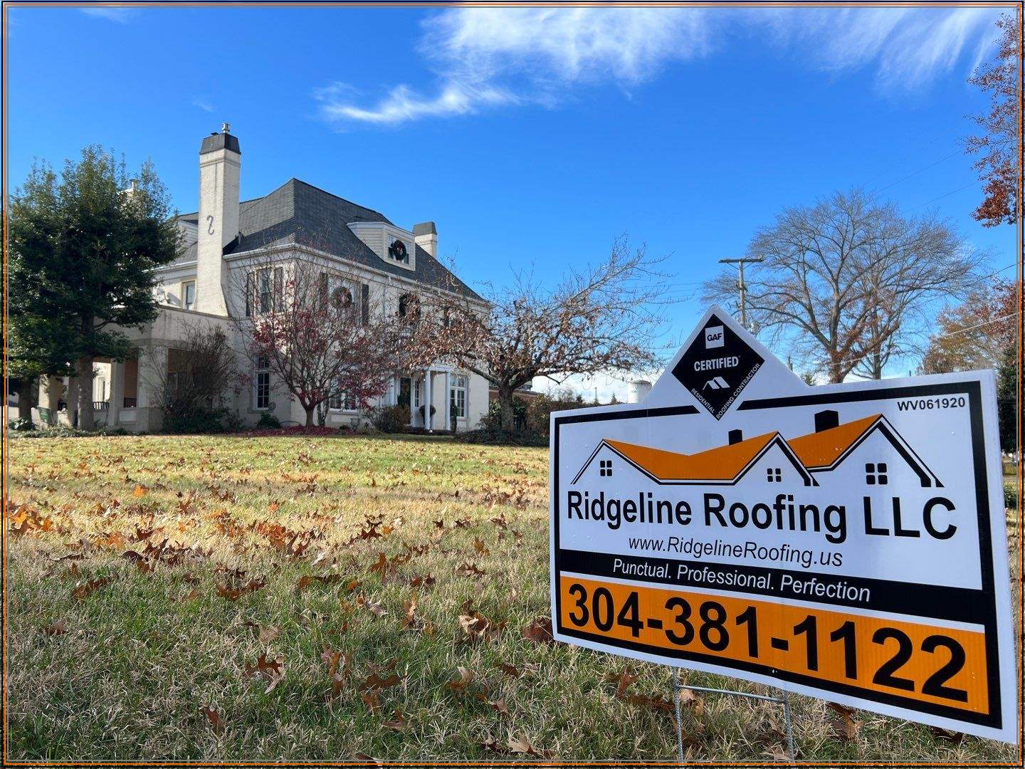 Ridgeline Roofing yard sign in front of a stately home with charcoal shingles