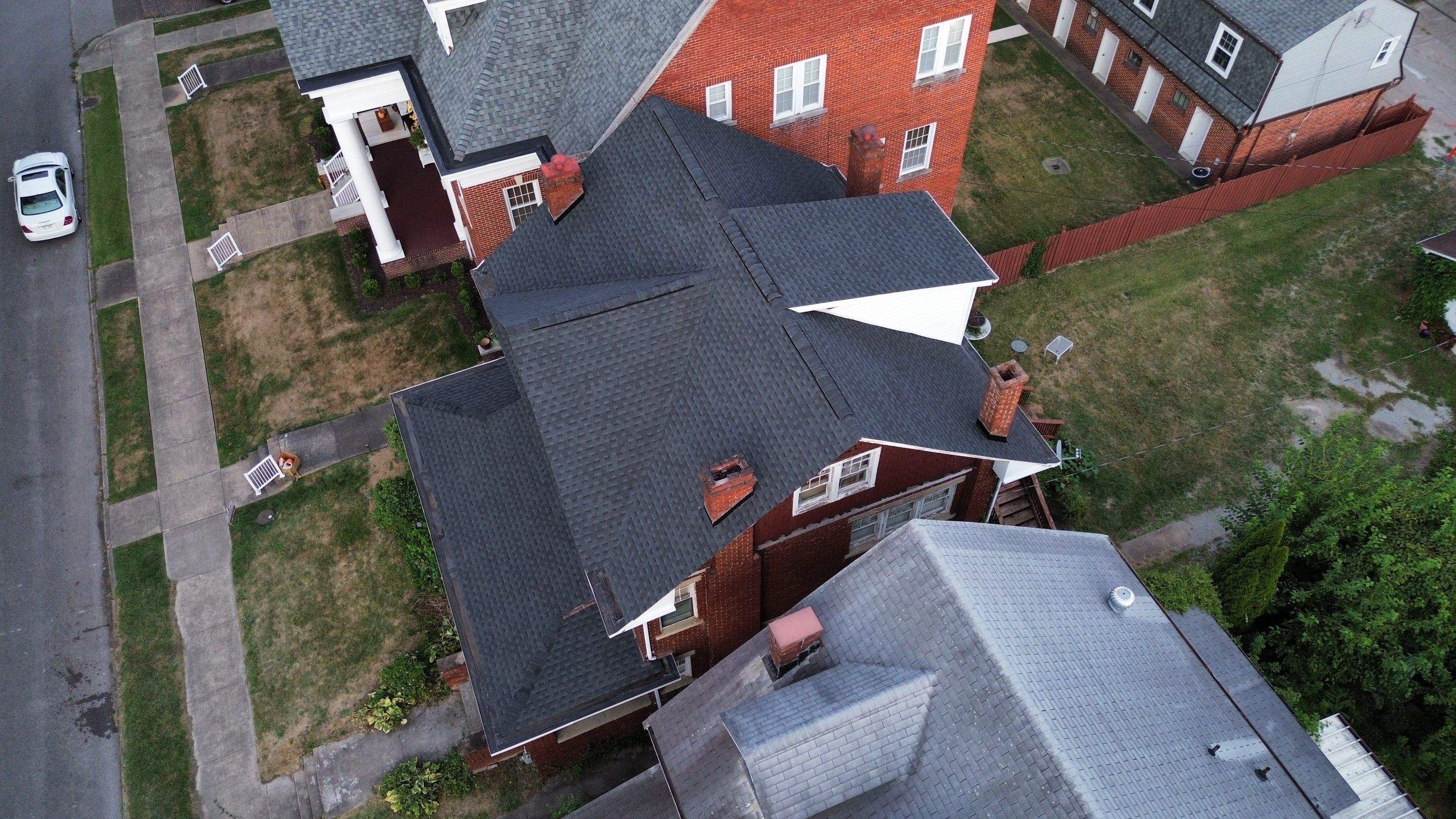 Charcoal shingles on a multi-story brick home with chimneys