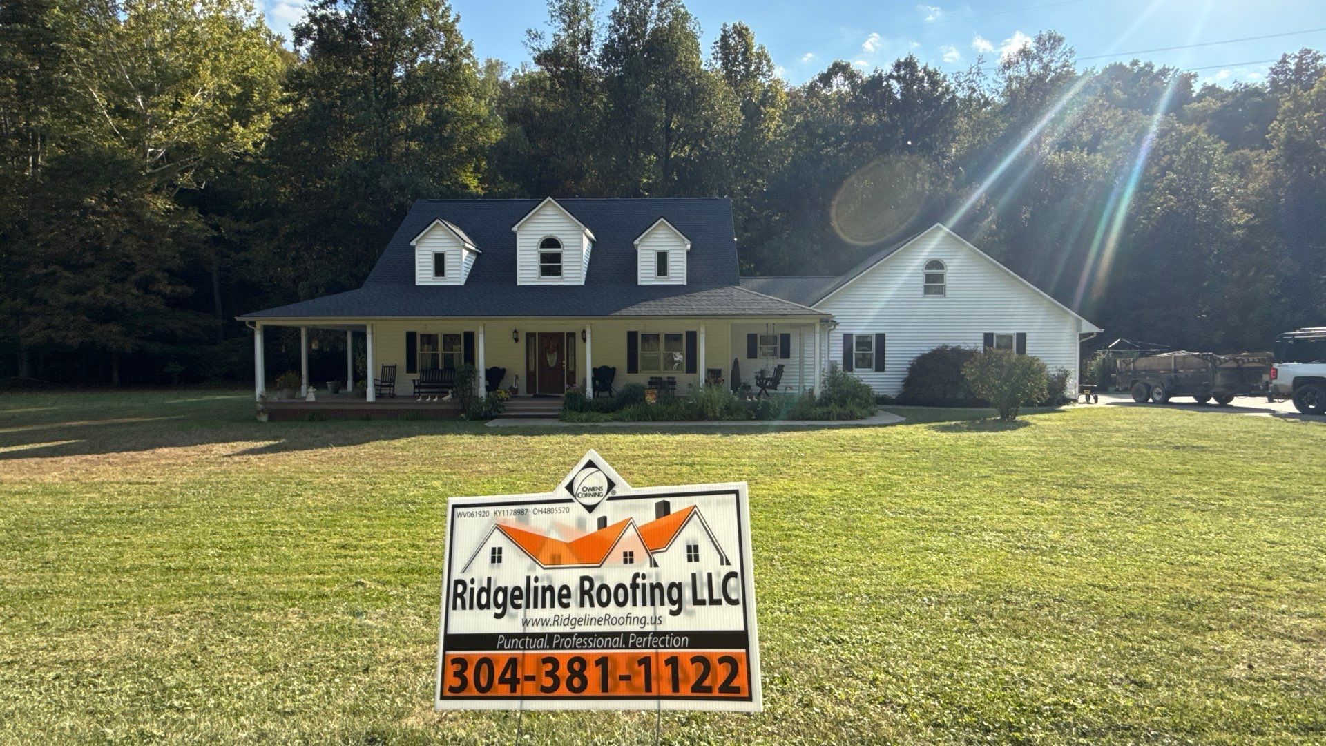 Ridgeline yard sign at a white home with charcoal roof