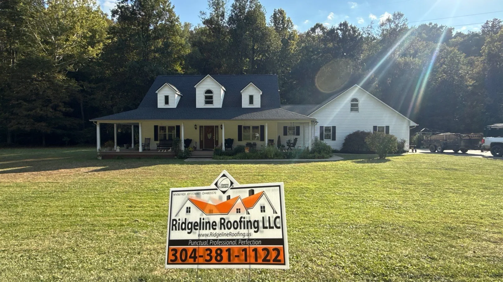 Ridgeline yard sign at a white home with charcoal roof